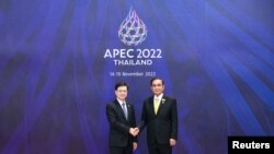 香港特首李家超(左)2022年11月18日在出席亚太经合组织峰会期间与东道主泰国总理握手。(亚太经合组织2022年峰会照片)