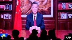 2023 年 12 月 31 日,人们在一家餐厅吃晚饭,屏幕上播放着中国国家主席习近平在北京发表新年讲话的画面。(法新社)