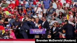 美国共和党总统候选人、美国前总统唐纳德·特朗普(Donald Trump)在宾夕法尼亚州巴特勒的竞选集会上被枪手击中右耳,随后美国特勤局人员将他搀扶起来。(2024年7月13日)