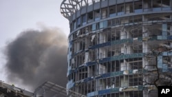 俄罗斯导弹袭击基辅后,浓烟从一座受损建筑的后面升起。(2023年12月29日)