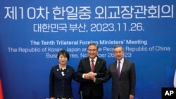 资料照片:2023年11月26日,中国外交部长王毅(右)、韩国外长朴振(中)和日本外相上川洋子在韩国釜山举行的三方外长会议前合影留念。(美联社照片)
