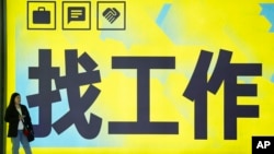 一名女子站在北京一个地铁站张贴的“找工作”的广告牌前。(2024年7月2日)