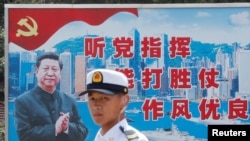 资料照:一名中国解放军海军士兵在香港的海军基地站在有着中国领导人习近平画像的宣传标语前。(2016年7月8日)