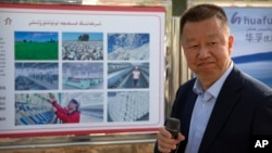 资料照:中国政府组织外国记者参观新疆维吾尔自治区阿克苏期间,新疆华孚色纺集团有限公司总经理李强在其公司宣传板前讲话。(2021年4月20日)