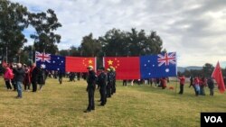 在澳大利亚国会大厦外的草坪上,欢迎中国总理李强到访的人群展示中澳两国国旗。(2024年6月17日)