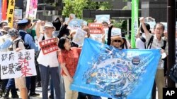 2023年8月24日,在东京电力公司控股公司(TEPCO)总部前,一名抗议者在集会上举着标语牌,反对受损的福岛核电站排放经过处理的放射性水。