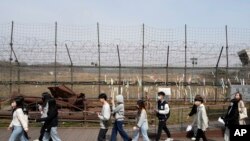 资料照片:2023年3月24日,人们经过靠近朝鲜边境的韩国坡州市临津阁的铁丝网。