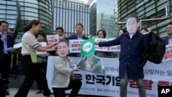 资料照片:韩国首尔的抗议者戴着印有日本首相岸田文雄和韩国总统尹锡悦头像的面罩,手拿着显示Line应用程序的标牌。(2024年5月14日)