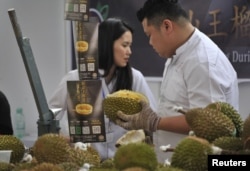 资料照:中国广西壮族自治区南宁举行的马来西亚榴莲节的促销员在猫山王榴莲摊位前工作。 (2017年11月4日)