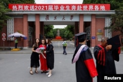 资料照:上海复旦大学学生在校门拍摄毕业照。(2021年6月25日)