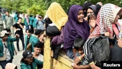 Người tị nạn Rohingya Muslim được đưa khỏi trung tâm tạm trú Balai Meuseuraya Aceh trong lúc sinh viên biểu tình phản đối
