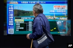台湾强震后,东京一名男子驻足观看日本一家电视台播放对冲绳地区的海啸警报。(2024年4月3日)