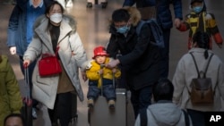 北京西站,2023年1月18日,一位男士推着坐在手提箱上的孩子。中国人口出生率开始缓慢下降,使中国领导人面临新的考验。