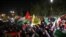 Para demonstran melambaikan bendera Iran dan Palestina saat demo di depan Kedutaan Besar Inggris di Teheran, Minggu, 14 April 2024, setelah Iran meluncurkan serangan drone dan misil ke Israel. (Foto: Atta Kenare/AFP)