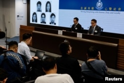 香港当局在记者会上公布被通缉的五名活动人士的照片。(2023年12月14日)