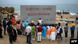 到中国福建省平潭岛旅游的游客参观台湾海峡边树立起的一块距离台湾68海里的石碑。(2024年1月13日)
