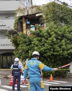 日本西南部宫崎市的警察站在被地震毁坏的建筑物旁警戒。(2024年8月8日)