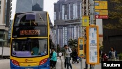 香港居民在一处住宅楼建筑工地前排队上公交车。(2024年2月27日)