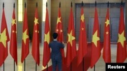 资料照:一名男子在越南国会大厦内整理中越两国国旗准备迎接中国领导人习近平的到访。(2015年11月6日)