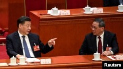 在北京人民大会堂举行的全国人民代表大会第四次全体会议上,中国国家主席习近平与中国总理李强交谈。(2023年3月11日)