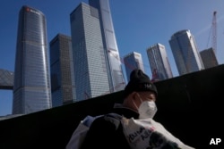 一名打工人扛着他的行李行走在北京商务区。(2023年3月15日)