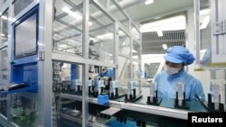资料照片:中国广东东莞一家生产电动汽车锂离子电池的工厂工人在生产线上。(2022年10月16日)
