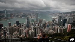 资料照片:一名游客在维多利亚山顶地区架起相机,拍摄香港的天际线。(2019年9月1日)