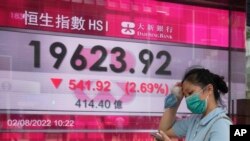 周二香港街头,一名女子走过恒生指数显示大跌的电子显示牌。(2022年8月2日)