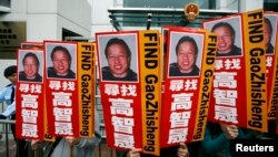 资料照:香港民众在中联办前手举多年失踪的中国著名维权律师高智晟的画像与标语。(2010年2月4日)