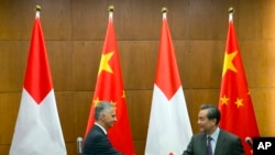 2016年1月15日,瑞士外交部长迪迪埃·伯克哈尔特(Didier Burkhalter)同中国外长王毅在中国外交部召开的联合记者会结束时握手。-美联社资料照