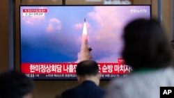 2022年5月25日,在韩国首尔的一个火车站,人们正在观看有关朝鲜导弹发射的新闻节目。