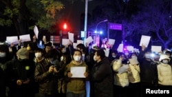 2022年11月28日,在中国北京,随着新冠肺炎疫情的持续,人们在为乌鲁木齐火灾遇难者守夜后,手持白纸抗议新冠肺炎疫情限制措施。