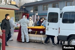 北京一家火葬场工作人员将灵柩移下车。(2022年12月17日)