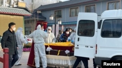 北京一家火葬场工作人员将灵柩移下车。(2022年12月17日)
