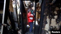 一名妇女在乌克兰顿涅茨克地区被俄罗斯攻击摧毁的住宅中取出衣服(2022年12月10日)