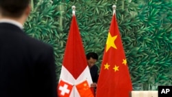 中国和瑞士官员会谈前,中国工作人员正在布置会场。桌上摆放的和背景是中国和瑞士两国国旗。