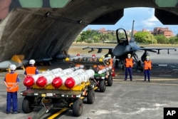 台湾军队士兵站在F16V战机前,准备进行装载美制AGM-84鱼叉反舰导弹及AIM-120和AIM-9空空导弹的训练。(2022年9月16日)