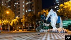 上海封城后,一名快递员将食物袋送到一个住宅小区大门外。(2022年4月11日)