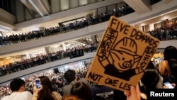香港抗议者在中环国际金融中心手举“五项诉求,缺一不可”的标语牌大合唱《愿荣光归香港》。