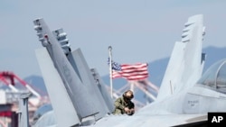 2022年9月23日,美国士兵在抵达韩国釜山港口的核动力航空母舰罗纳德·里根号的甲板上检查 F/A-18 超级大黄蜂战斗机。