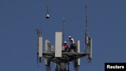 2020年5月6日,德克萨斯州西布鲁克,工人们在T-Mobile信号塔上安装5G电信设备