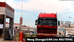中国发现非洲猪瘟后,河南省郑州肉类加工企业双汇集团大门处可以看到身着防护服的工人。(2018年8月17日)