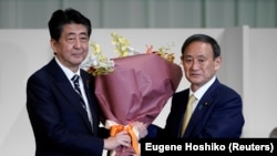 日本首相安倍晋三为在自民党总裁选举中获胜的日本官房长官菅义伟献花。(2020年9月14日)