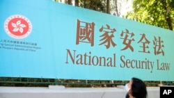 香港一名妇女走过街头的国安法宣传牌。(美联社2020年6月30日)