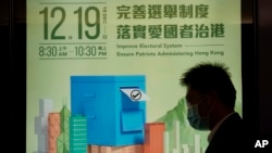 香港一行人走过呼吁港人踊跃投票的宣传广告。(美联社照)