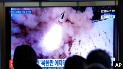 2022年1月20日,在韩国首尔的首尔火车站,人们观看电视上播放的朝鲜导弹发射的画面。