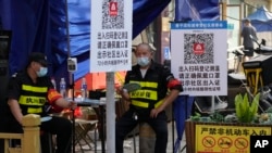 资料照:北京街头两名保安把守需要扫健康码和社区出入证方能出入的社区入口。(2022年6月20日)