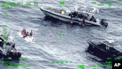 资料照片:美国海岸警卫队公布的照片显示人们在波多黎各西北的公海水域站在一艘倾覆的小船上。(2022年5月12日)