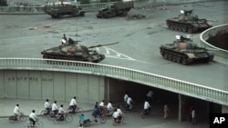 1989年6月6日星期二上午,在中国北京,天安门广场大屠杀发生两天后,自行车乘客稀少地穿过一条隧道,上面是天桥上部署的军用坦克。(美联社资料照片)