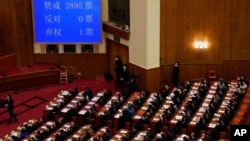 在北京人民大会堂举行的全国人民代表大会闭幕会议上,代表们在屏幕旁鼓掌,屏幕上显示了支持赋予亲北京的委员会权力以任命更多香港立法会议员的投票数。(2021年3月11日)